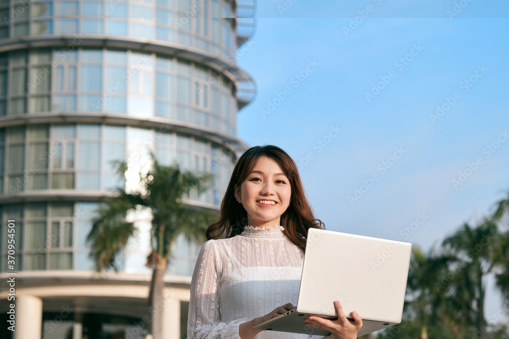 Portrait of cute young business woman outdoor with coffee and laptop