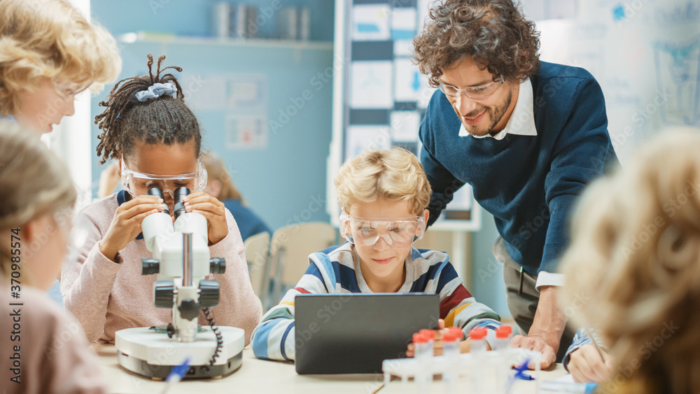 Elementary School Science Classroom: Cute Little Girl Looks Under Microscope, Boy Uses Digital Table