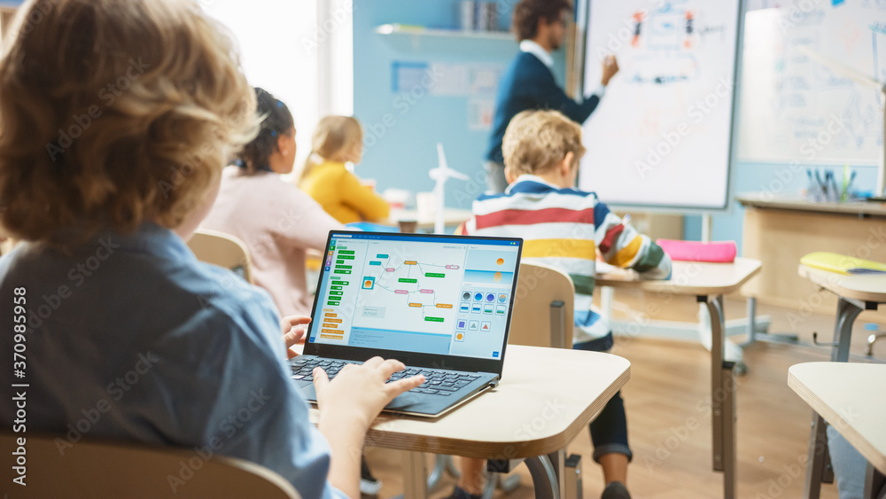 Elementary School Science Class: Over the Shoulder Little Boy Uses Laptop with Screen Showing Progra