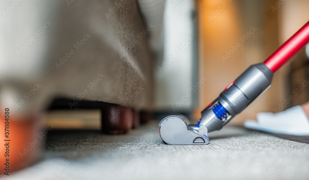  Modern vacuum cleaner while vacuuming. woman using a vacuum cleaner while cleaning carpet in the ho