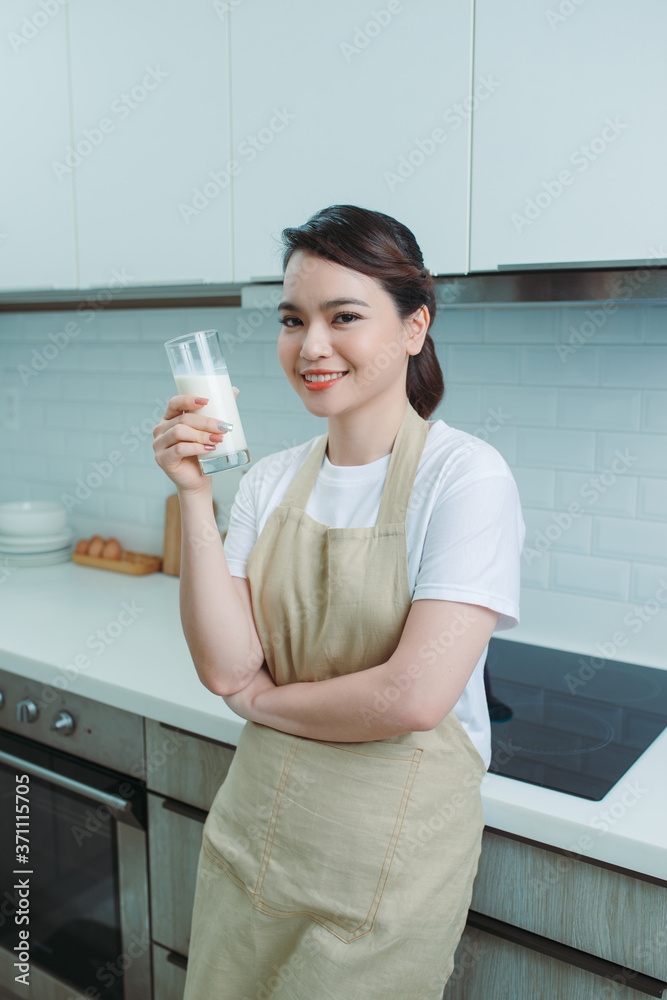 Happy young girl drink a milk for breakfast in kitchen conner. Healthy eating and lifestyle concept.