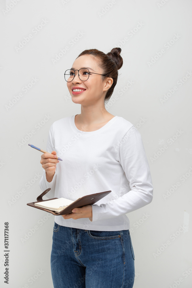 Serious pensive student girl reading her notes, holding pen and open notebook