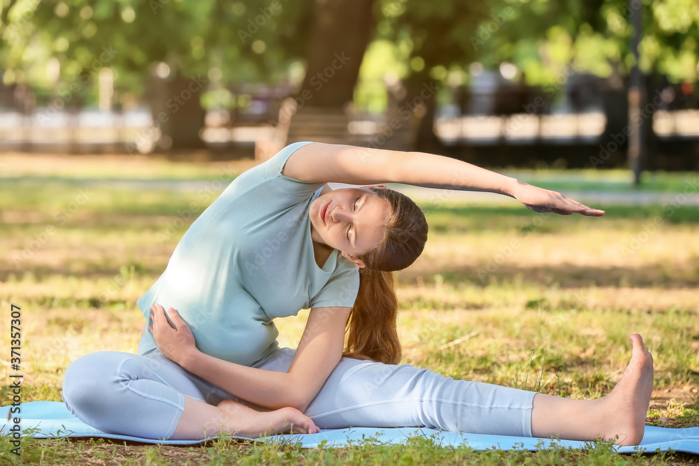 Young pregnant woman practicing yoga outdoors