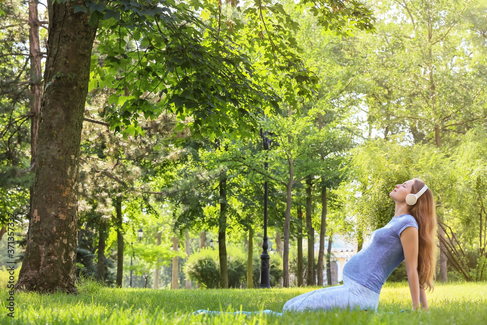 Young pregnant woman practicing yoga outdoors