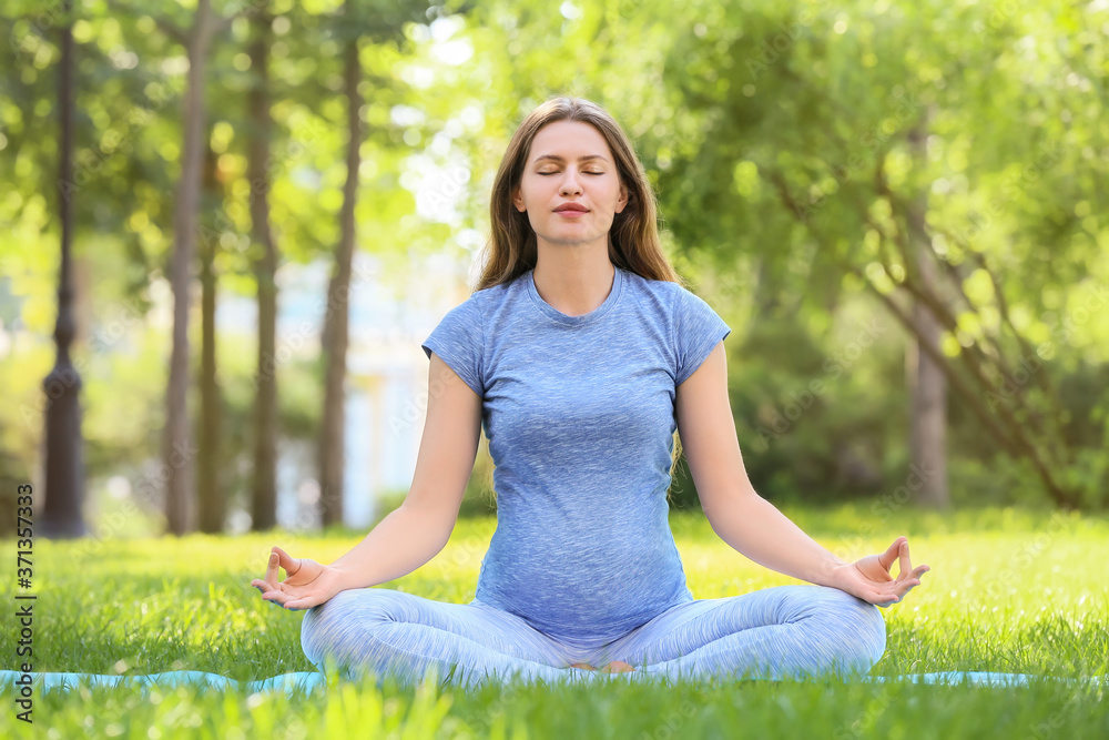 Young pregnant woman practicing yoga outdoors