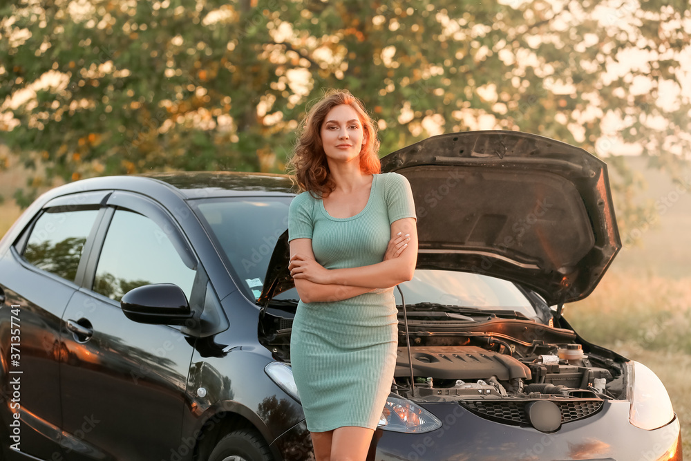 Young woman near broken car in countryside