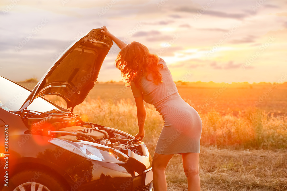 Young woman near broken car in countryside