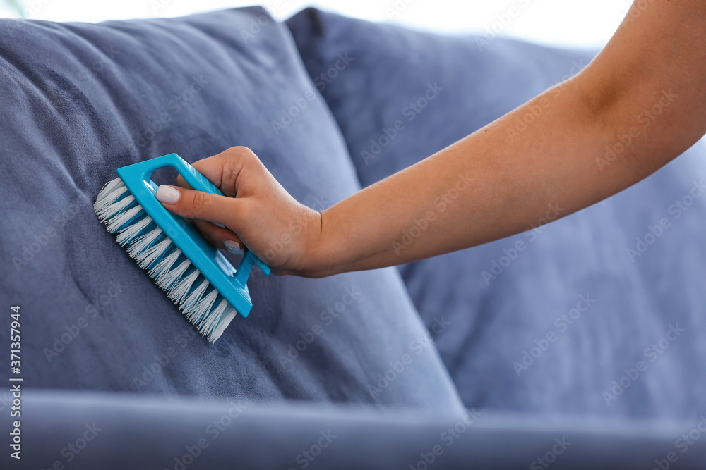 Woman removing dirt from sofa at home