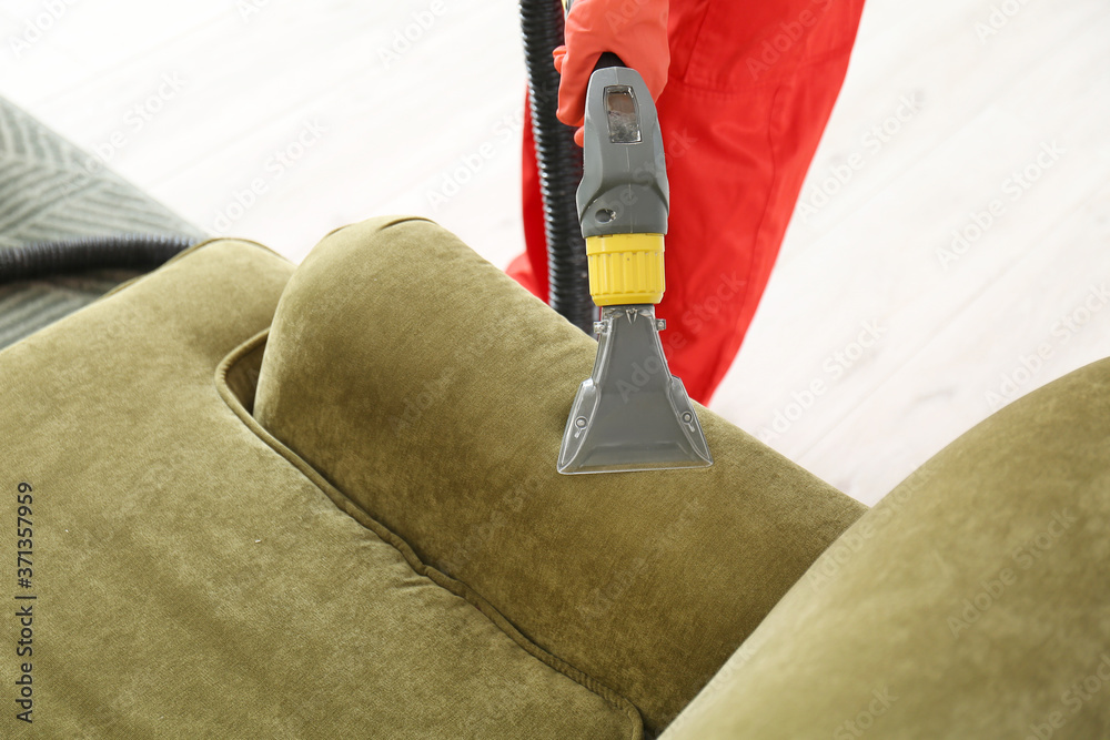 Dry cleaners employee removing dirt from sofa in house