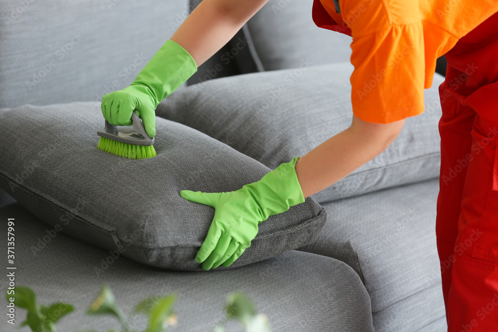 Dry cleaners employee removing dirt from sofa in house