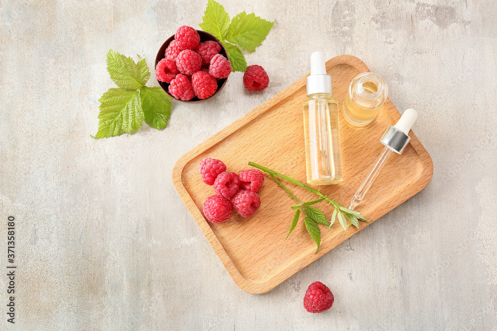 Bottles of raspberry essential oil on grey background