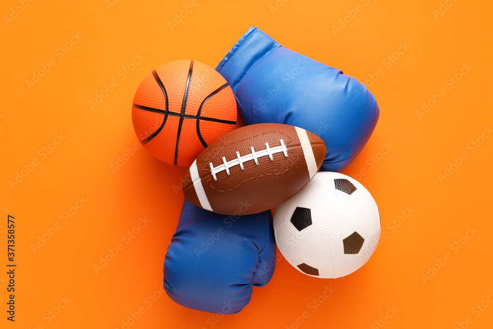 Sports balls with boxing gloves on color background