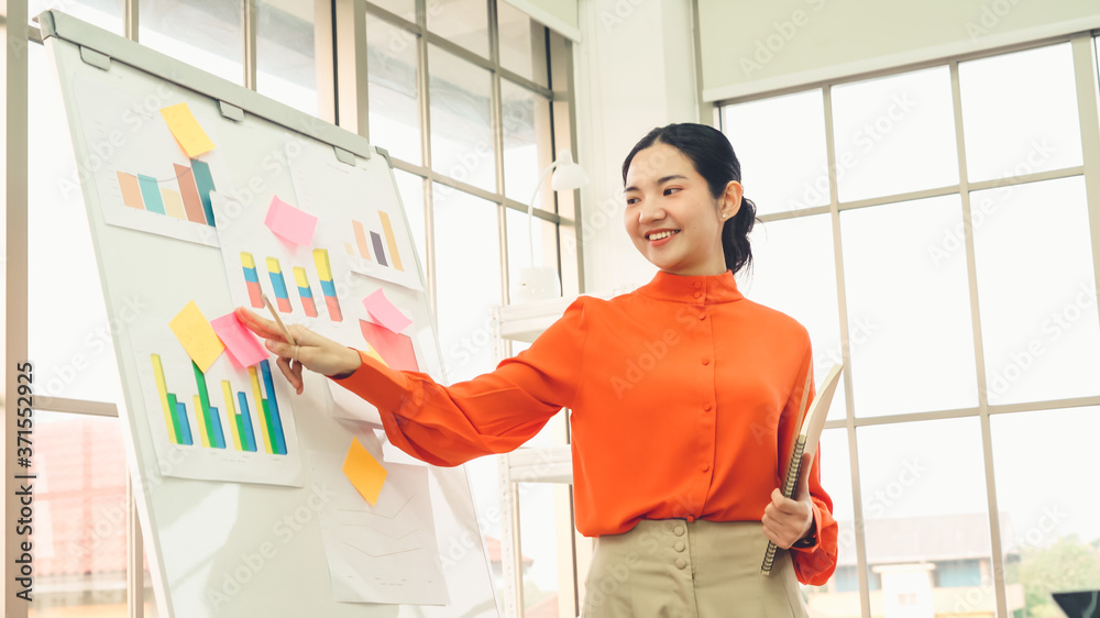 Young woman explains business data on white board in casual office room . The confident Asian busine