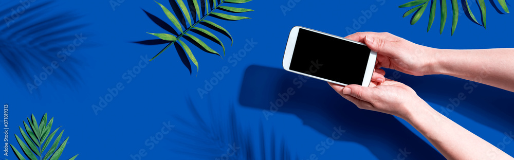 Smartphone with tropical palm leaves and shadow - flat lay