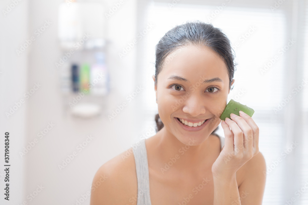 亚洲女人在浴室里把芦荟涂在脸上。