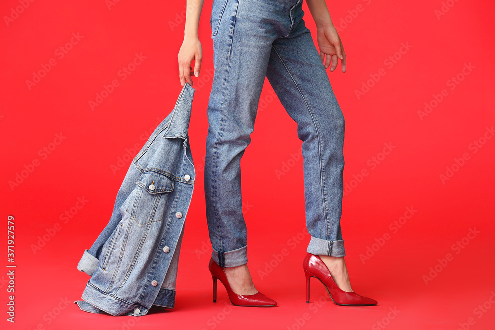 Beautiful young woman in jeans clothes on color background