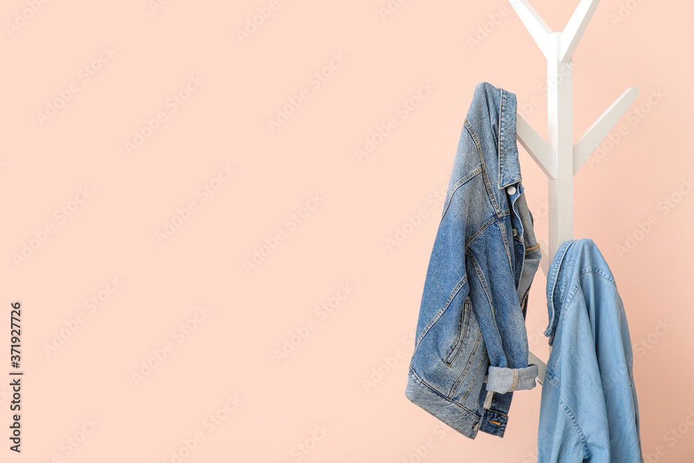 Jeans clothes hanging on rack near color wall