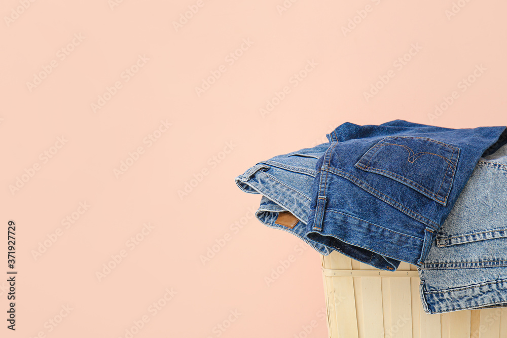 Basket and jeans clothes near color wall