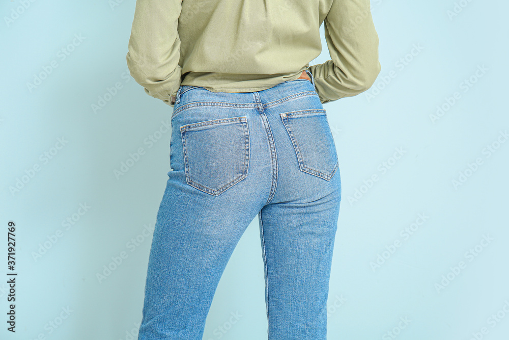 Beautiful young woman in jeans on color background