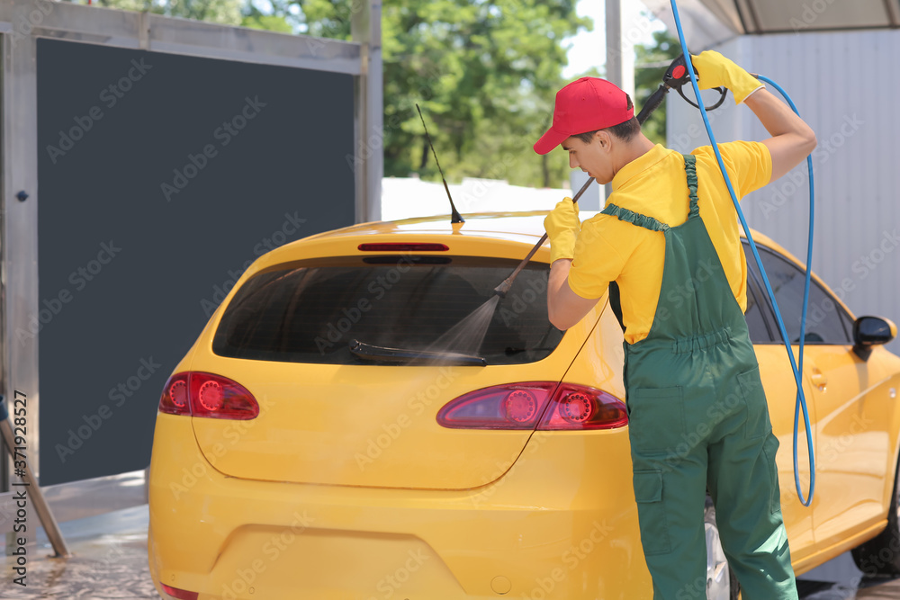 Worker of car wash cleaning modern automobile