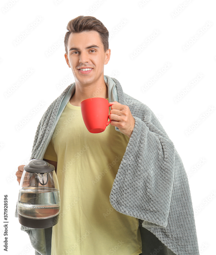 Young man with electric kettle and cup on white background