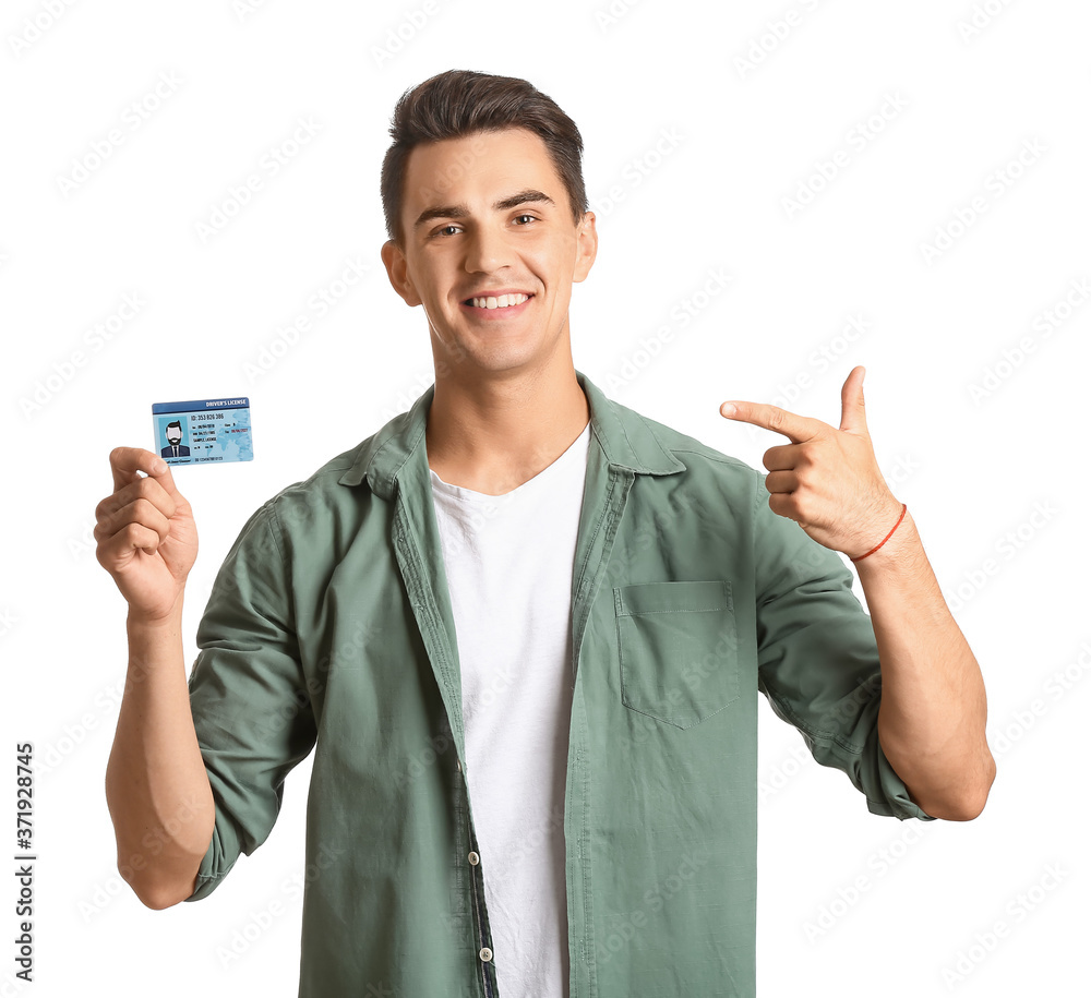 Young man with driving license on white background