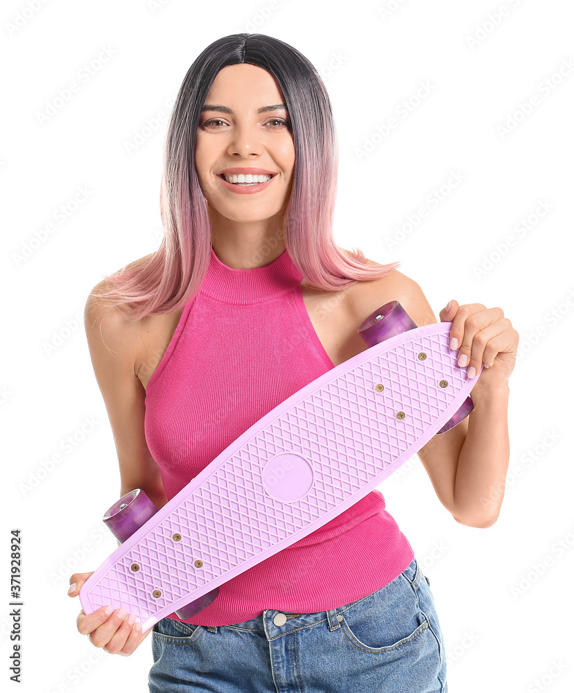 Beautiful young woman in wig and with skateboard on white background