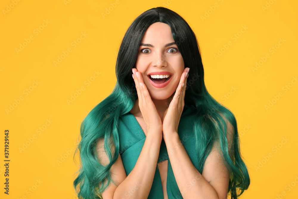 Beautiful young woman in wig on color background