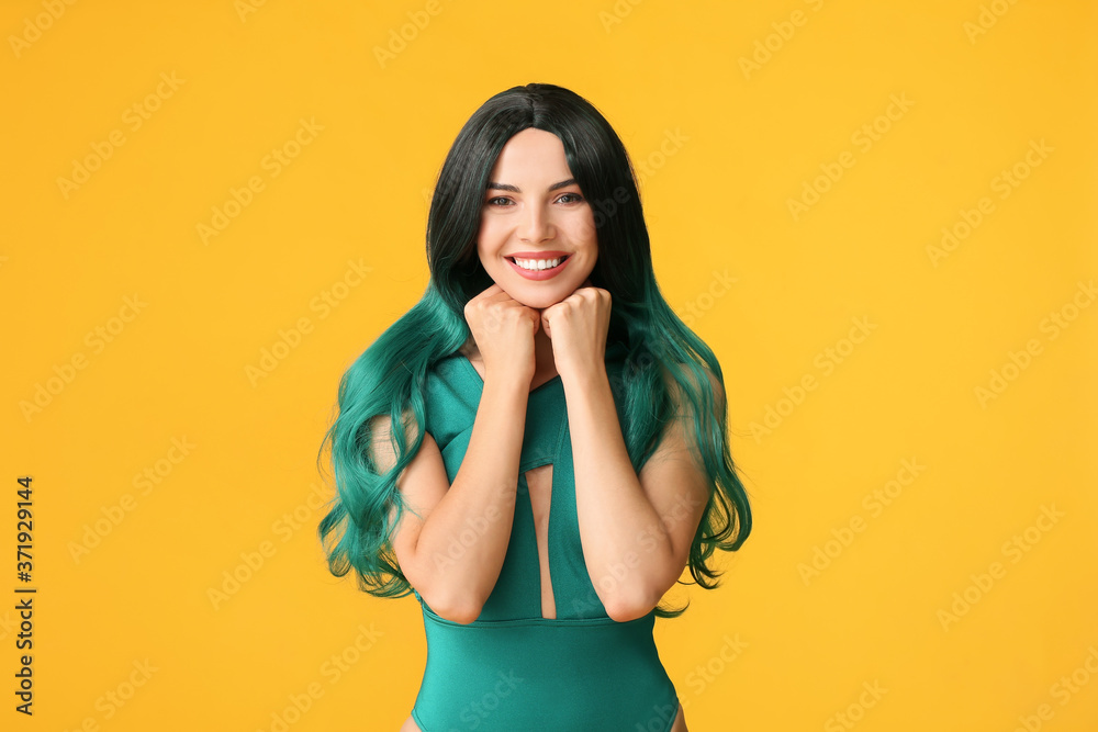 Beautiful young woman in wig on color background