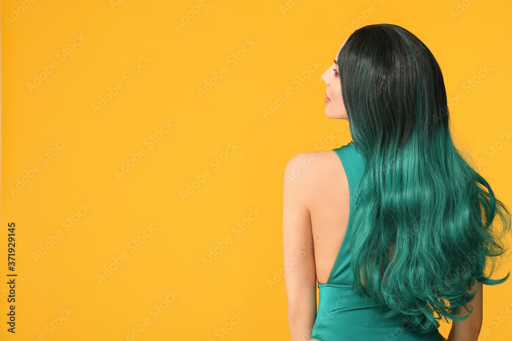 Beautiful young woman in wig on color background