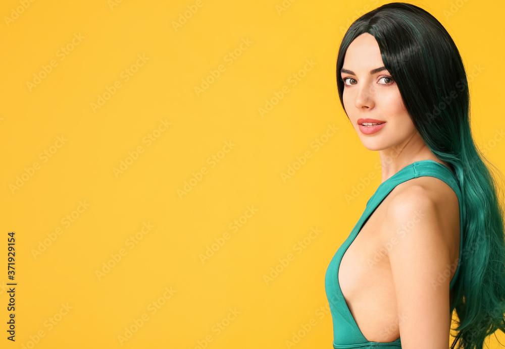 Beautiful young woman in wig on color background