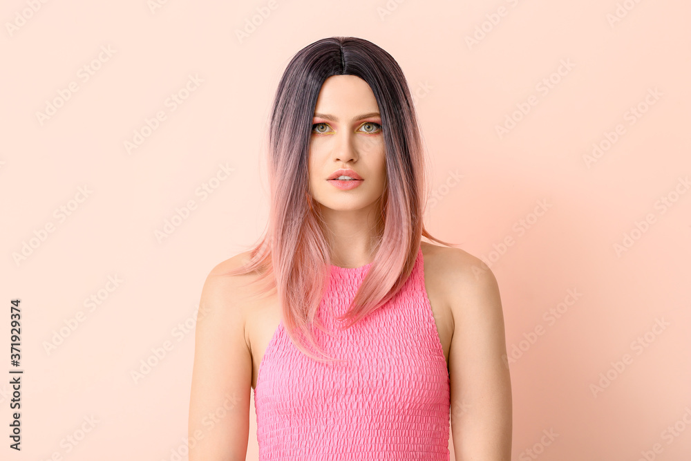 Beautiful young woman in wig on color background