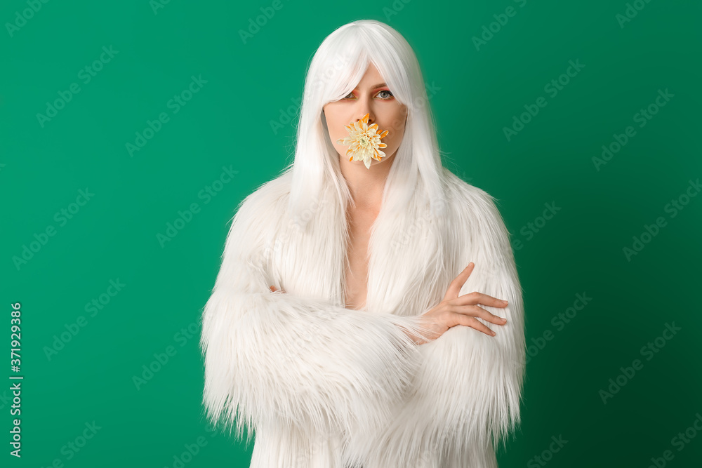 Beautiful young woman in wig on color background