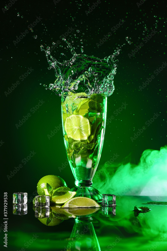 Glass of fresh mojito with splash on dark background