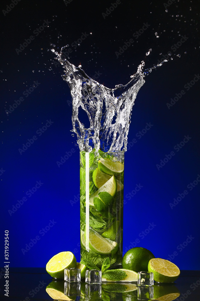 Glass of fresh mojito with splash on dark background