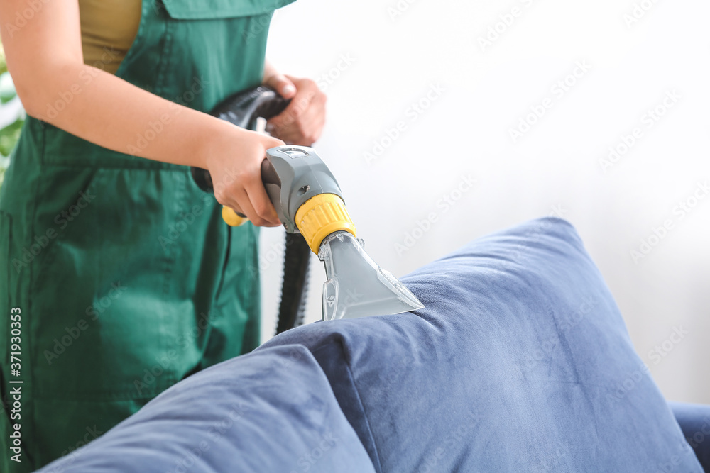 Dry cleaners employee removing dirt from sofa in house