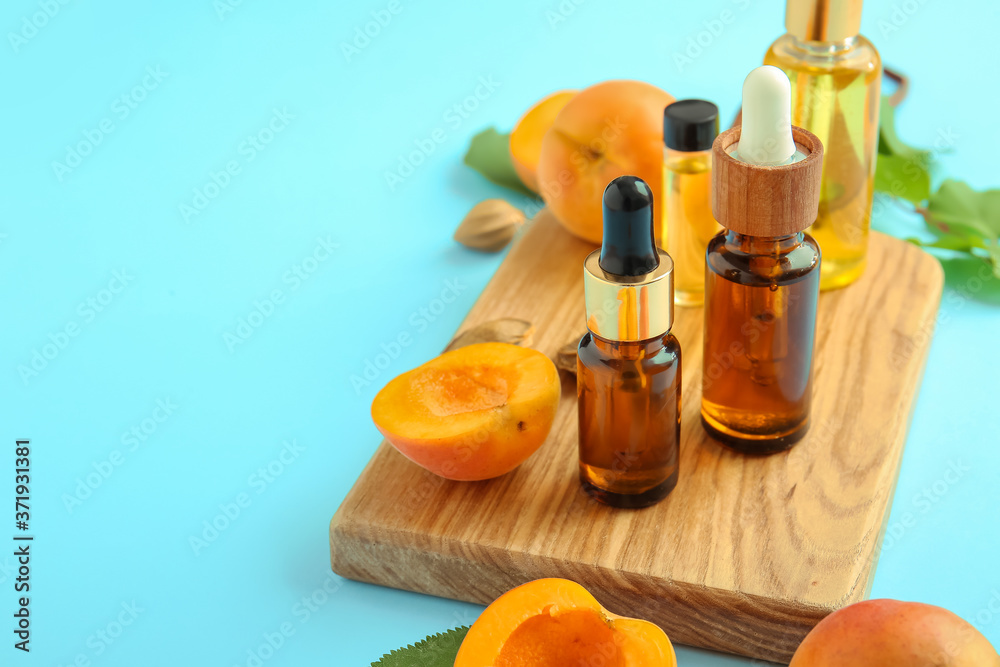 Bottles of apricot essential oil on color background