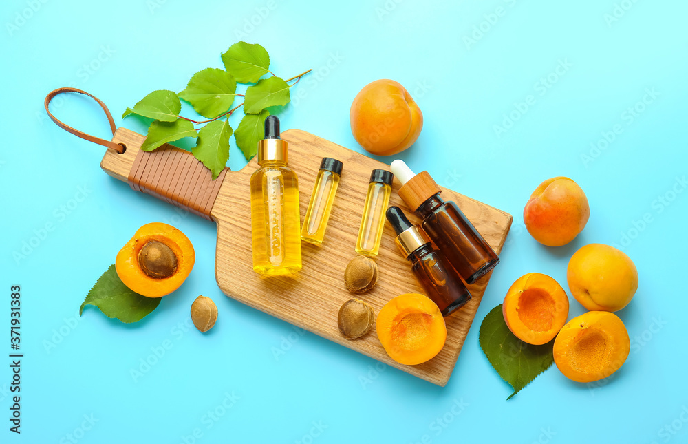 Bottles of apricot essential oil on color background