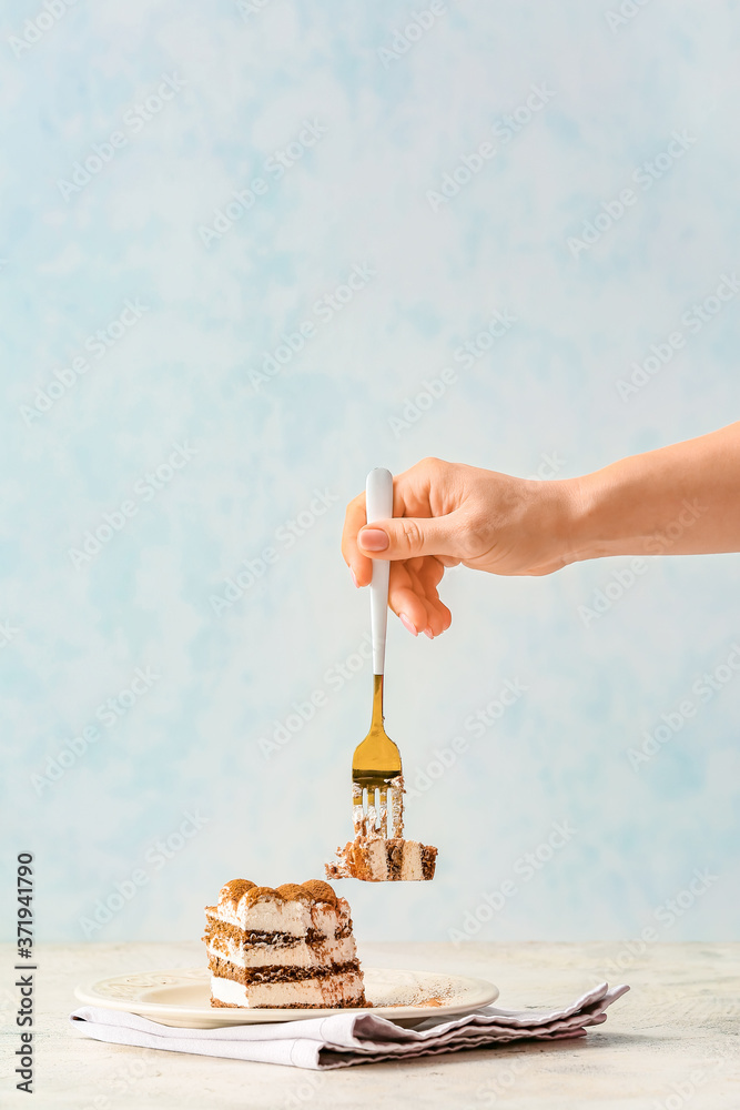 Woman eating tasty tiramisu at table