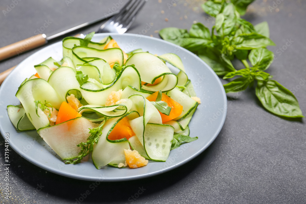 Plate with tasty cucumber salad on dark background