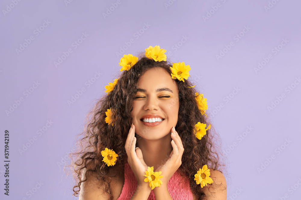 Young African-American woman with beautiful eyeshadows and flowers in her hair on color background