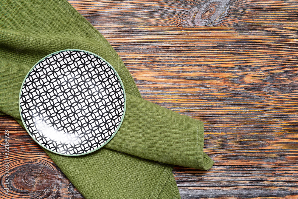 Clean plate with napkin on wooden background