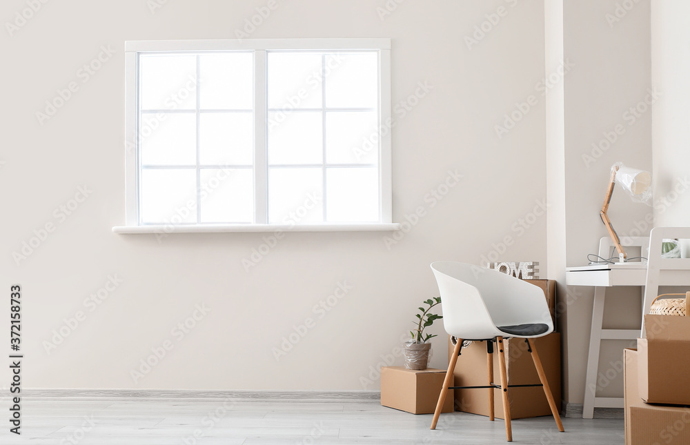 Cardboard boxes with belongings and table in new flat on moving day