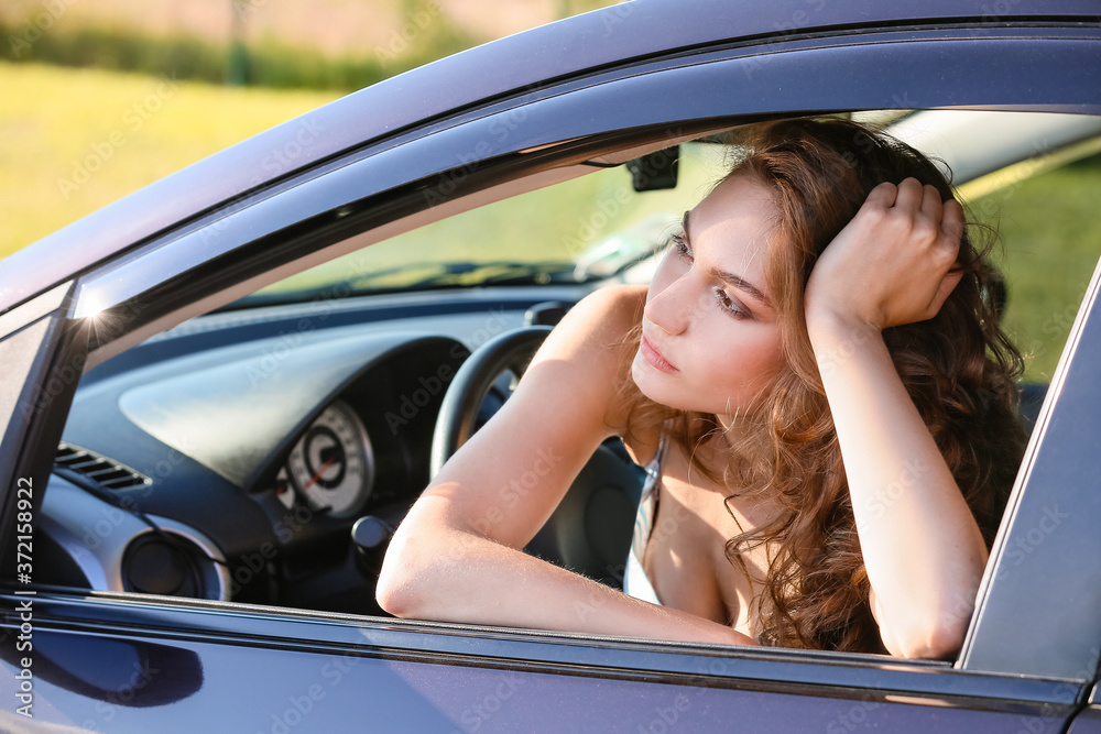 Stressed young woman sitting in car