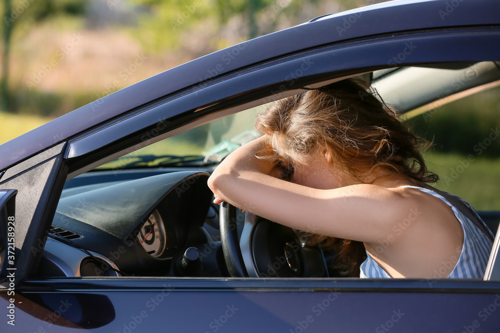 Stressed young woman sitting in car