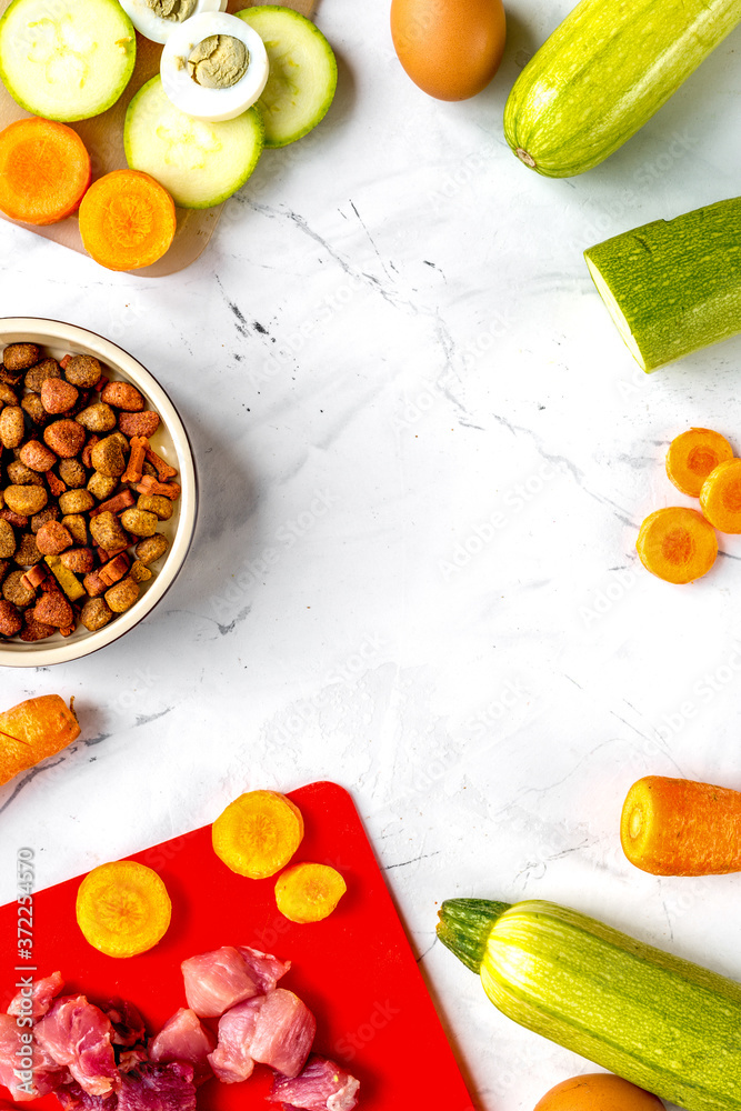 Bowl of dry dogfood, carrot, courgette, meat table background top view mock-up