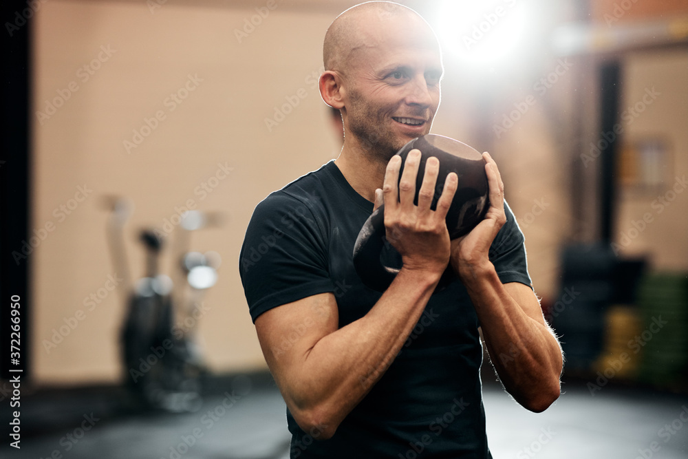 Smiling man working out with weights at the gym