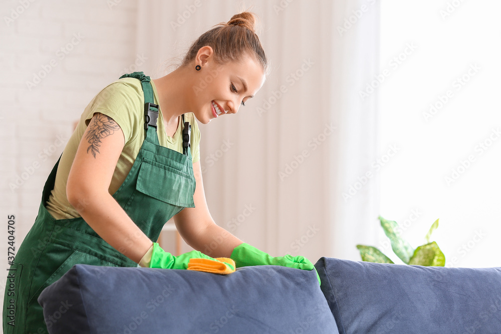 Dry cleaners employee removing dirt from sofa in house