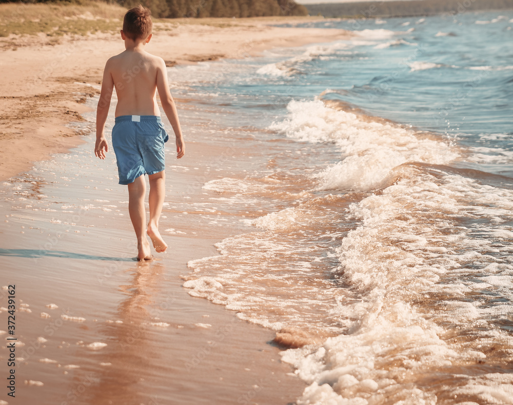 boy barefoot is jumping on the beach in water