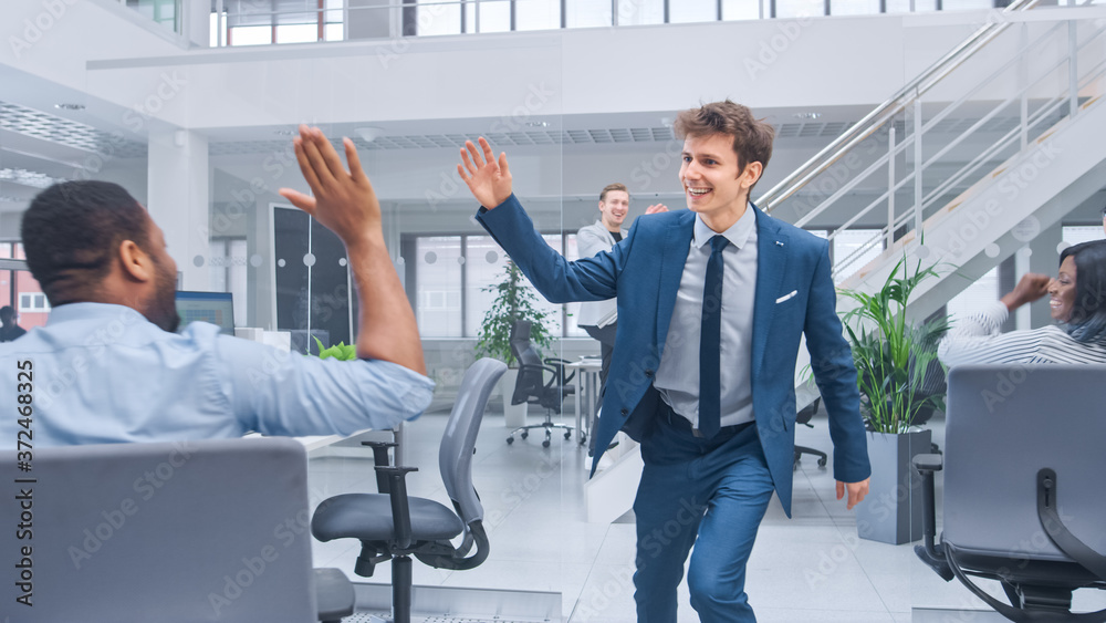 Young Happy Business Manager Wearing a Suit and Tie Dancing and Giving High Fives in the Office. Cel